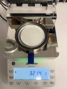 Moisture analyzer with milk loaded into the sample pan with filter paper underneath
